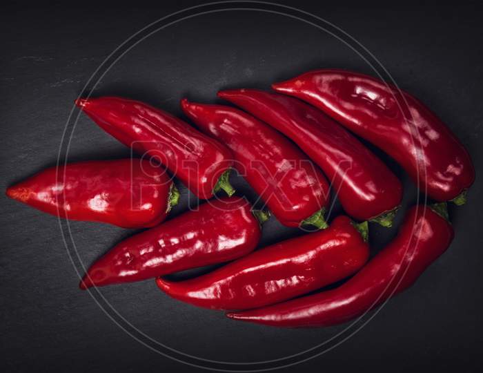 Close-Up Of Red Chili Peppers Against Black Background Long Red March Inspirational Scene