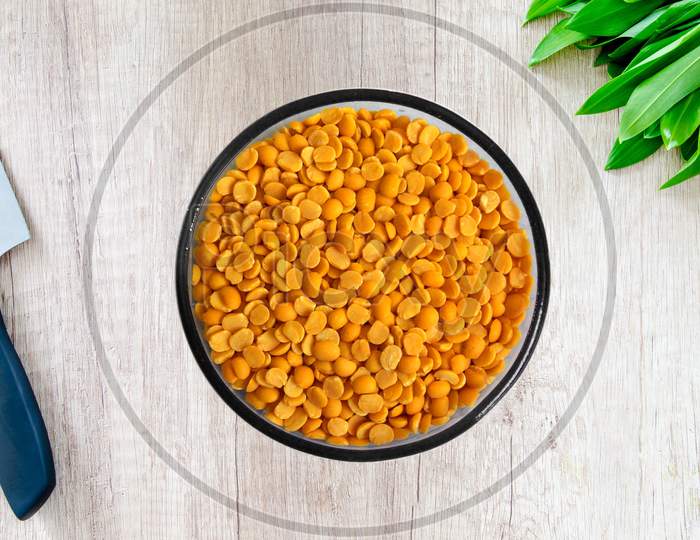 Yellow chopped peas in a bowal on wooden background.Yellow split chickpea peas boot chana dal lentil pulse bean on wooden background,top view.healthy food.