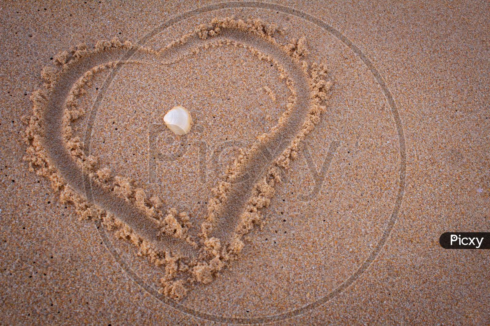 Beautiful Heart Symbol In Beach Sand With Sea Shell In Middle. Focus Set On Seashell.