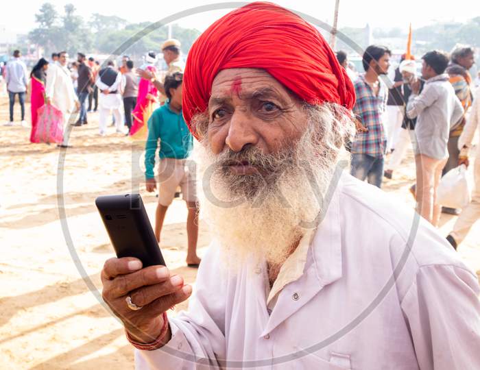 Pushkar, Rajashtan /India - 07/11/2019  Old man using mobile. Digitization of India in Villages . Indian telecommunication in villages.