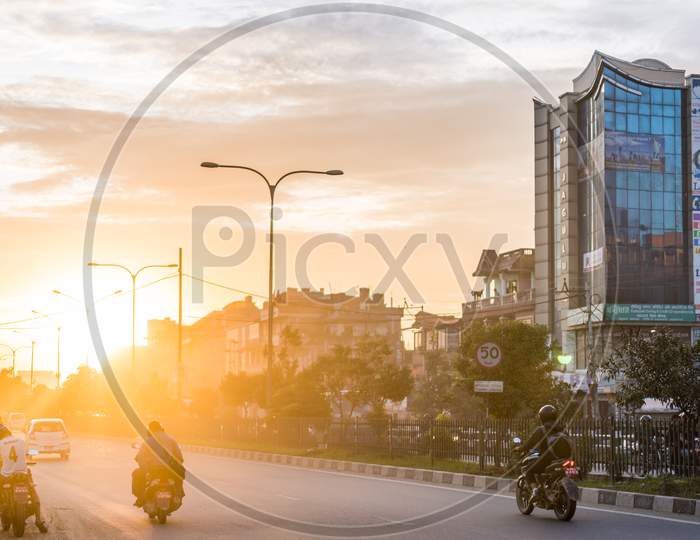 Street with scooter and motorcycles, tall building during sunset