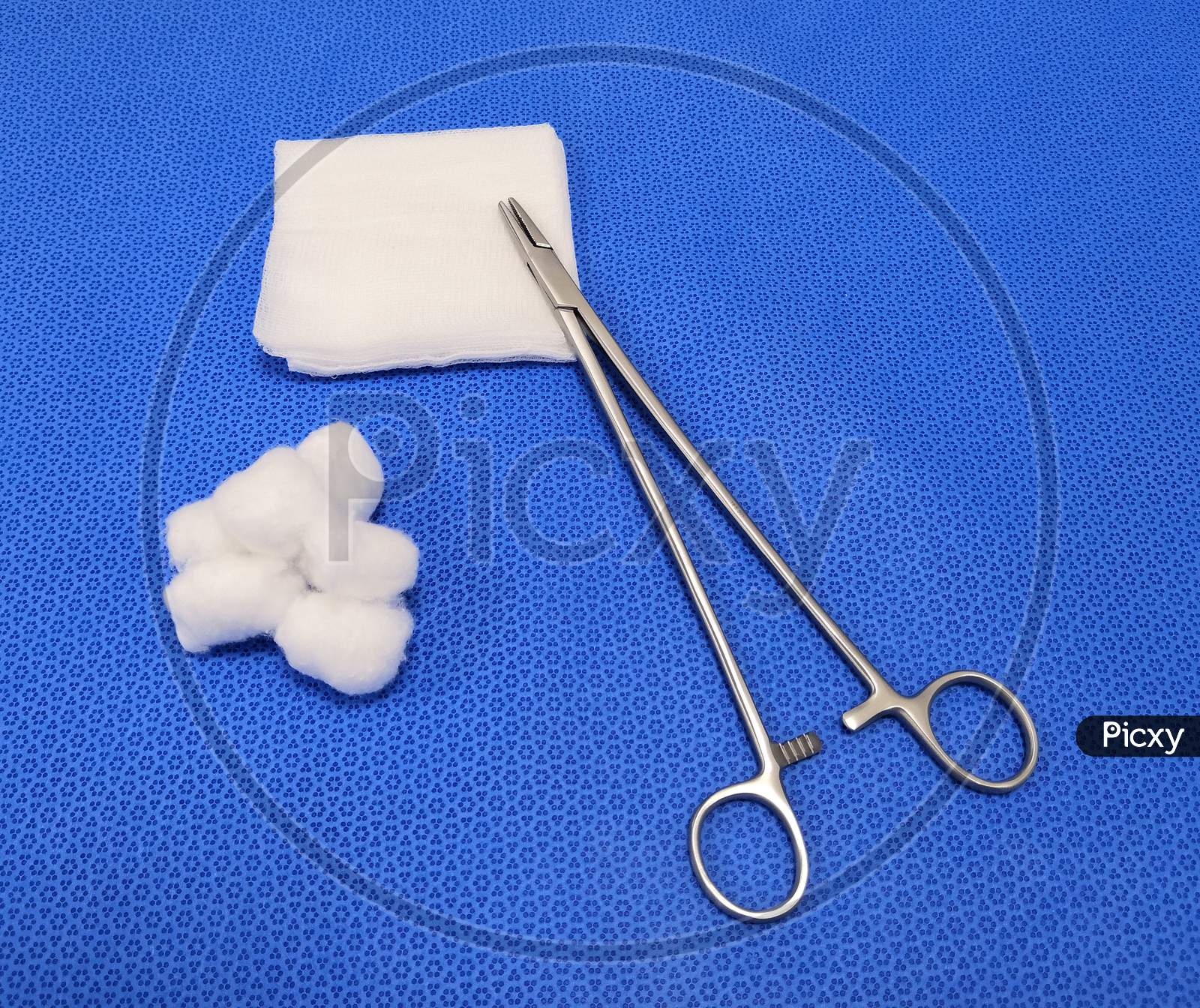 Surgical Needle Holder With Gauze And Cotton Swab In Blue Background