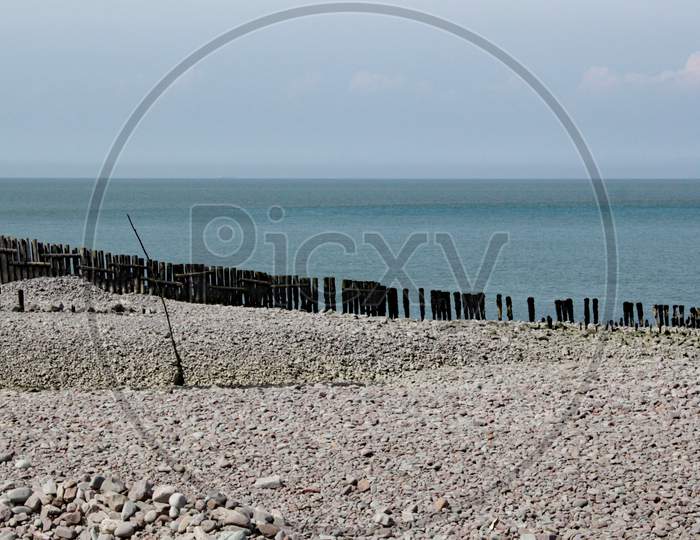 A Row Of Wooden Breakwaters Run Down To The Sea On A Pebble Beach At Porlock Weir In Somerset, Uk
