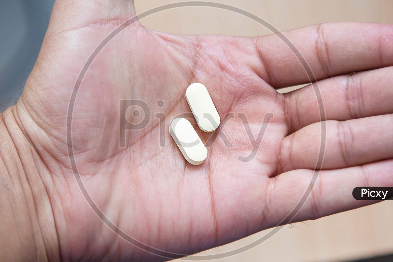 Hydroxychloroquine Tablet Medication For Treatment Malaria, And Potential New Drug Cure For Covid 19 Corona Virus Closeup. Therapy For Coronavirus. Pharmaceuticals On Wooden Table. Tablet In Hand.