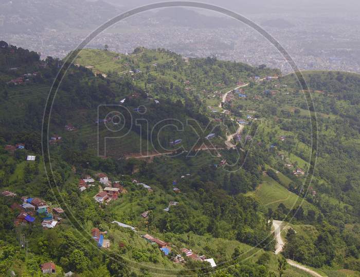 Green landscape from the top of a mountain with huts and roads