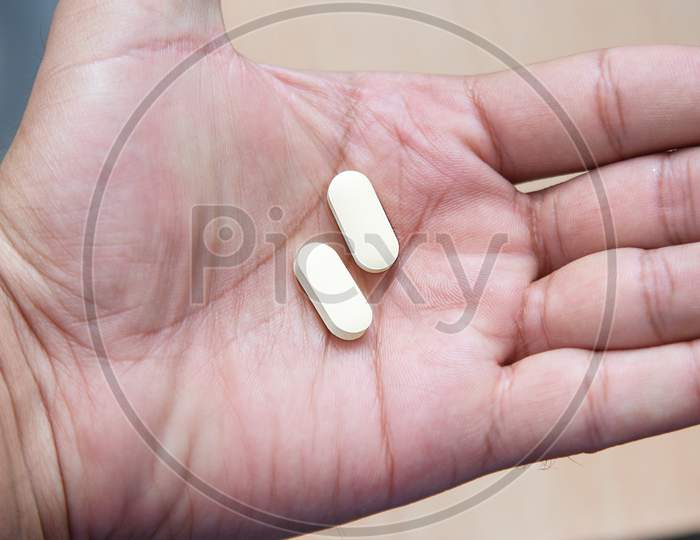 Hydroxychloroquine Tablet Medication For Treatment Malaria, And Potential New Drug Cure For Covid 19 Corona Virus Closeup. Therapy For Coronavirus. Pharmaceuticals On Wooden Table. Tablet In Hand.