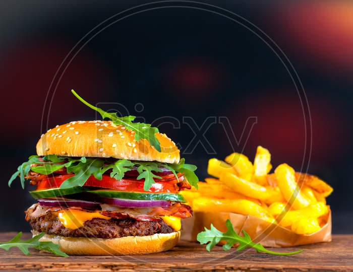 Burger and fries on wooden plate.