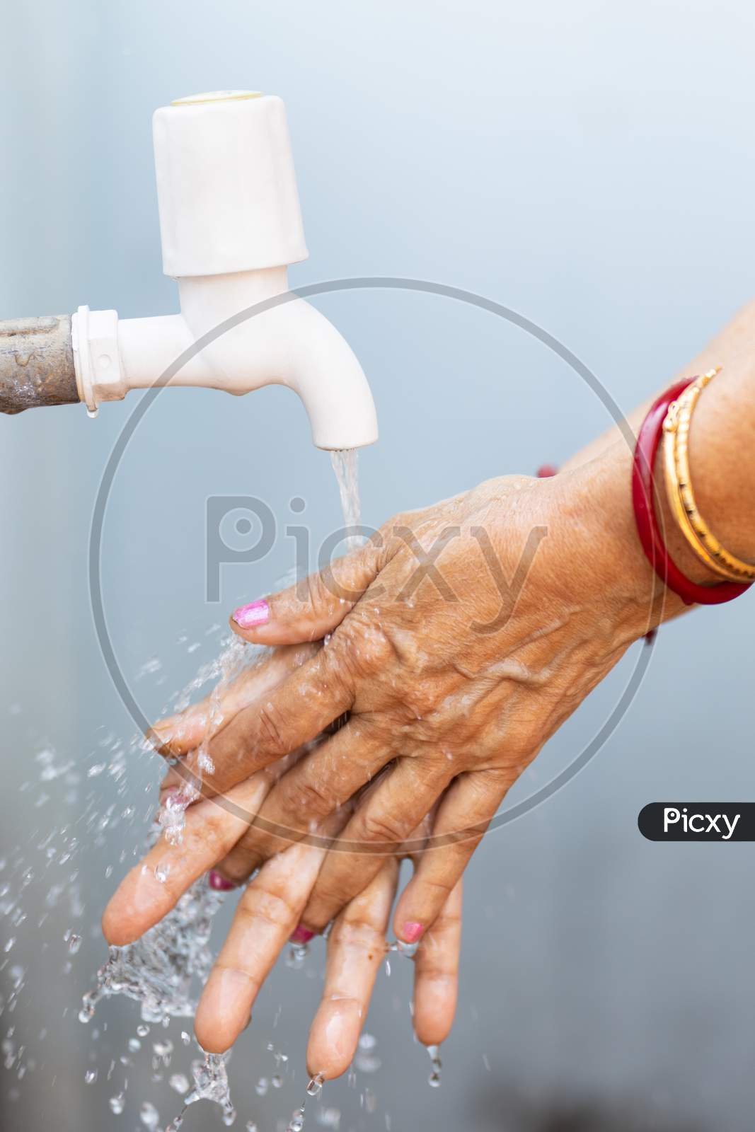 Senior Woman Washing Hand In Tap Water Outdoors