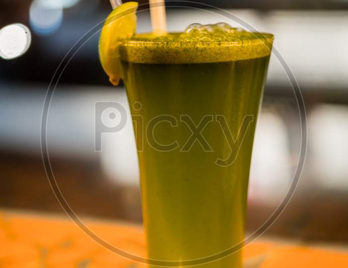 Mint lemonade with lemon slice, straw on a tall glass