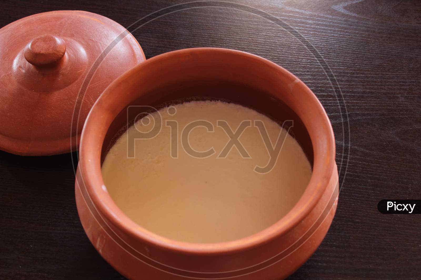 Curd/Yogurt in indian clay pot with wooden spatula