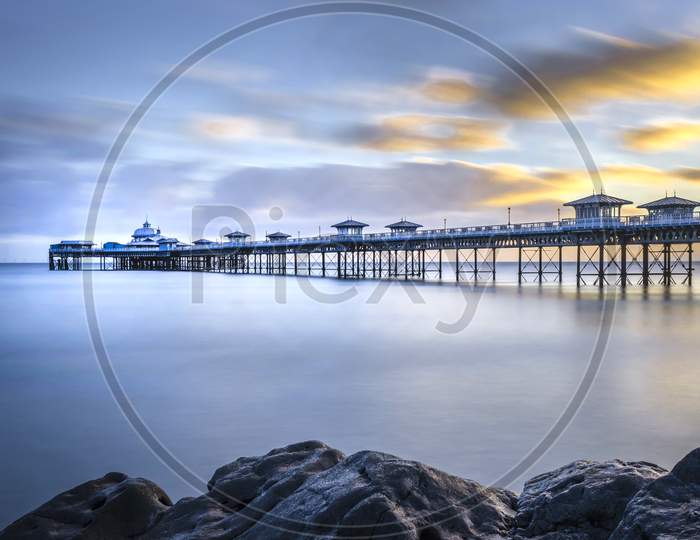 A morning shot of the Pier at Llandudno showing the calm water and floating clouds.