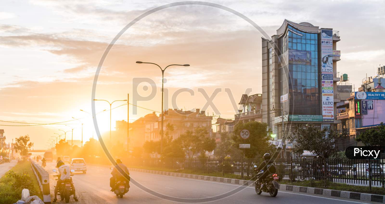 Street with scooter and motorcycles, tall building during sunset