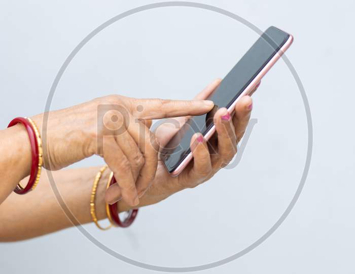 Senior Woman Hand Using Mobile Phone Against Plain Background