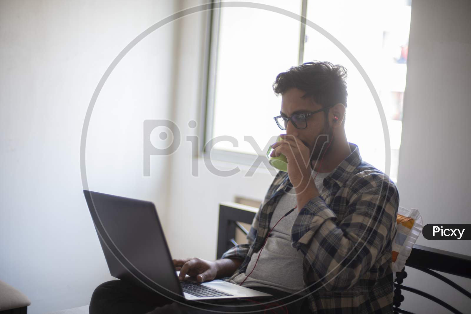 Indian Bengali handsome beard macho guy with laptop  having coffee/tea while doing office work from home. Indian lifestyle and work stress.