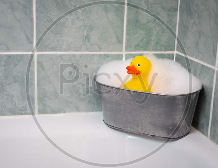 Yellow rubber duck in the bathtub with a soap and foam