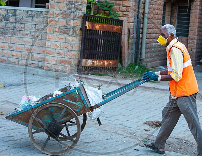 Jodhpur, Rajashtbn, India. 30 March 2020: Indian Man Wearing Mask Pulling Hand Cart Full Of Garbage Cleaning City Roads, Coronavirus, Covid-19 Outbreak, Swachh Bharat Mission.
