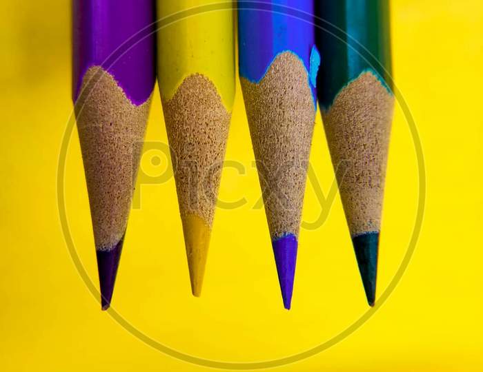 Four color pencils in yellow background