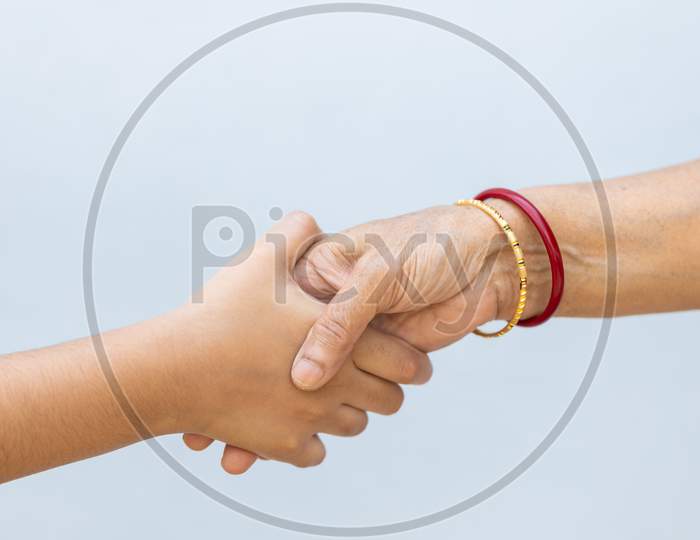 Senior Woman And Child Holding Hands Against Plain Background
