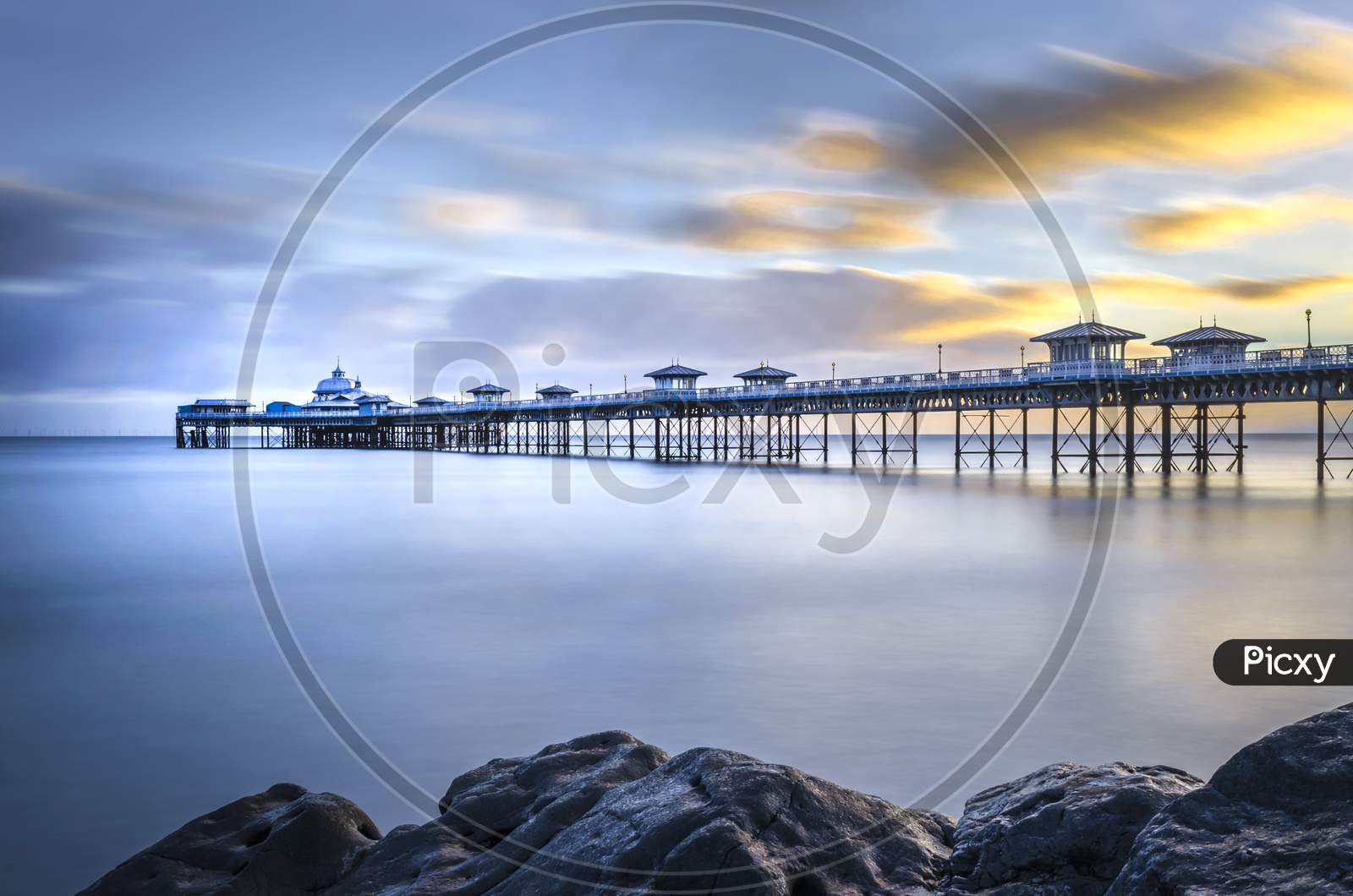 A morning shot of the Pier at Llandudno showing the calm water and floating clouds.