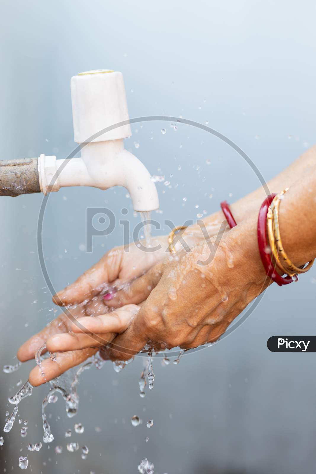 Senior Woman Washing Hand In Tap Water Outdoors