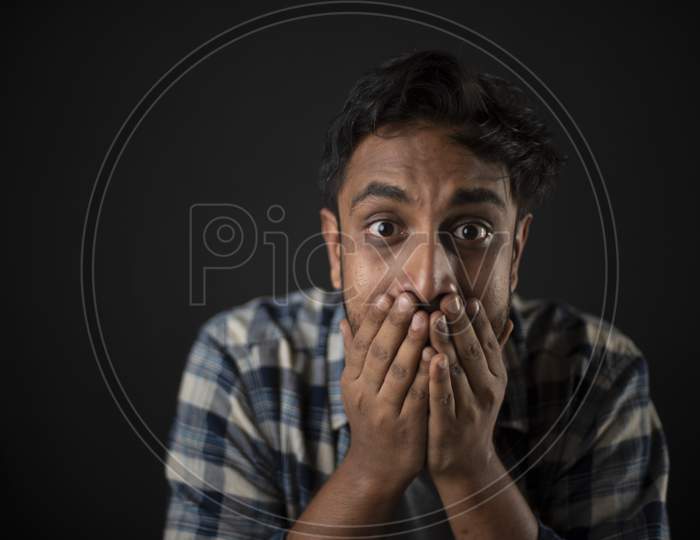 Indian Bengali handsome beard macho guy/man/male showing facial expressions depicting as dumb in front of a grey copy space studio background. Copy space facial expressions