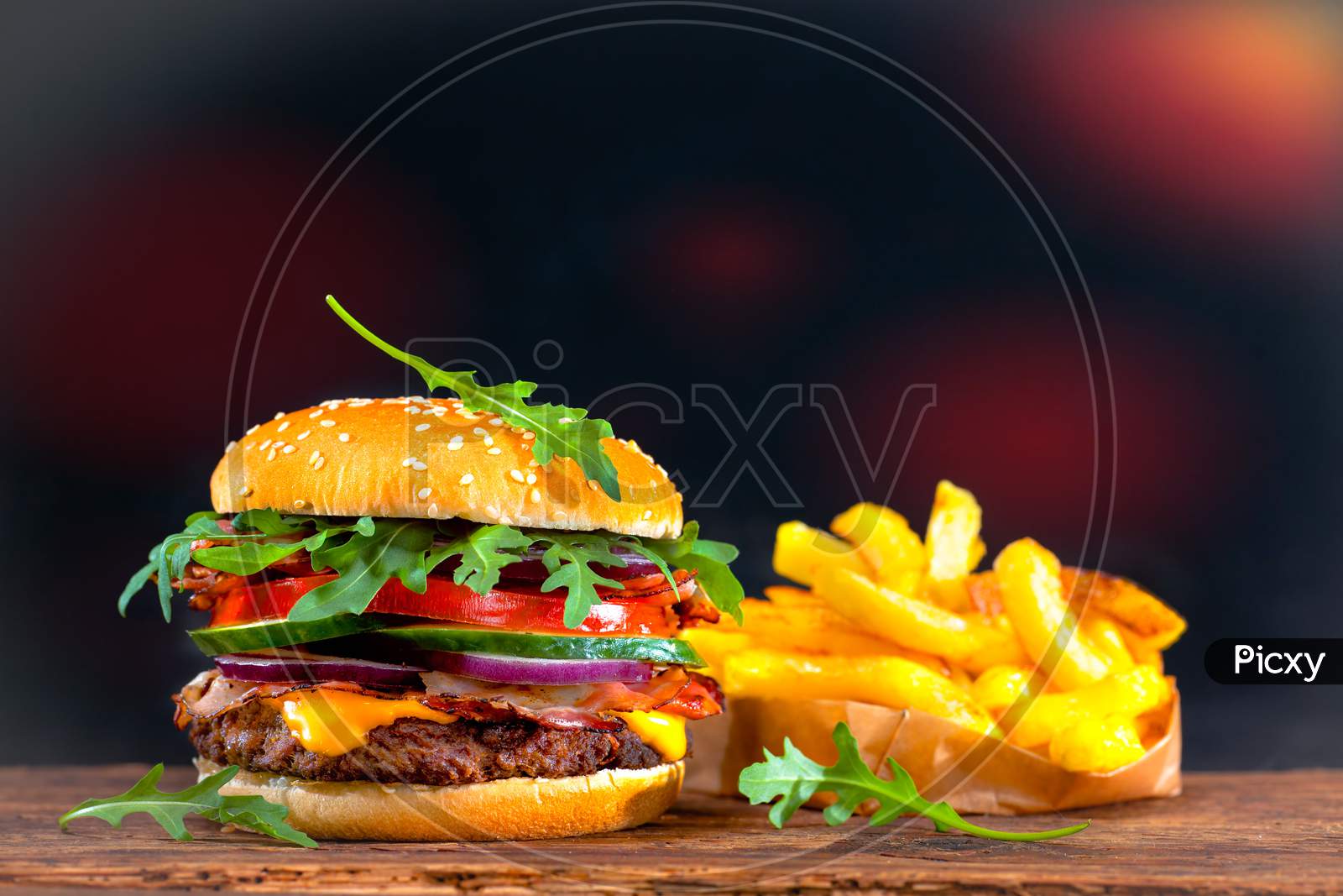 Burger and fries on wooden plate.