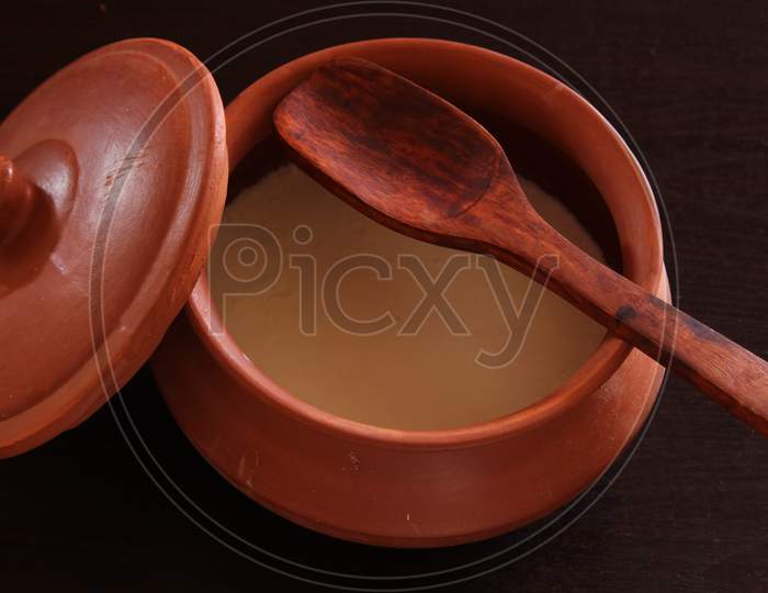 Curd/Yogurt in indian clay pot with wooden spatula