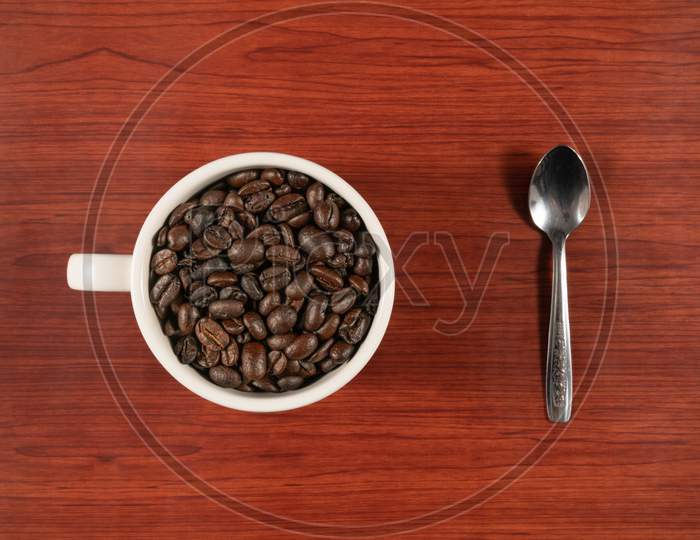 Coffee Beans In White Cup And Spoon With Wooden Background