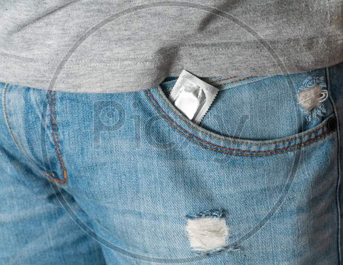 Condom In The Pocket Of Blue Men Jeans With A Zipper. Concept Of Sex, Seduction, Erotica, Protection, Safe Sex