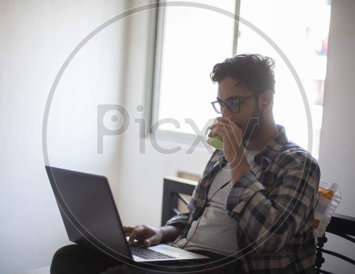 Indian Bengali handsome beard macho guy with laptop  having coffee/tea while doing office work from home. Indian lifestyle and work stress.