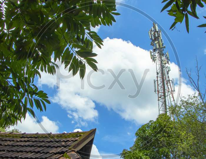 View through some trees on a 4G and 5G Telecommunication tower