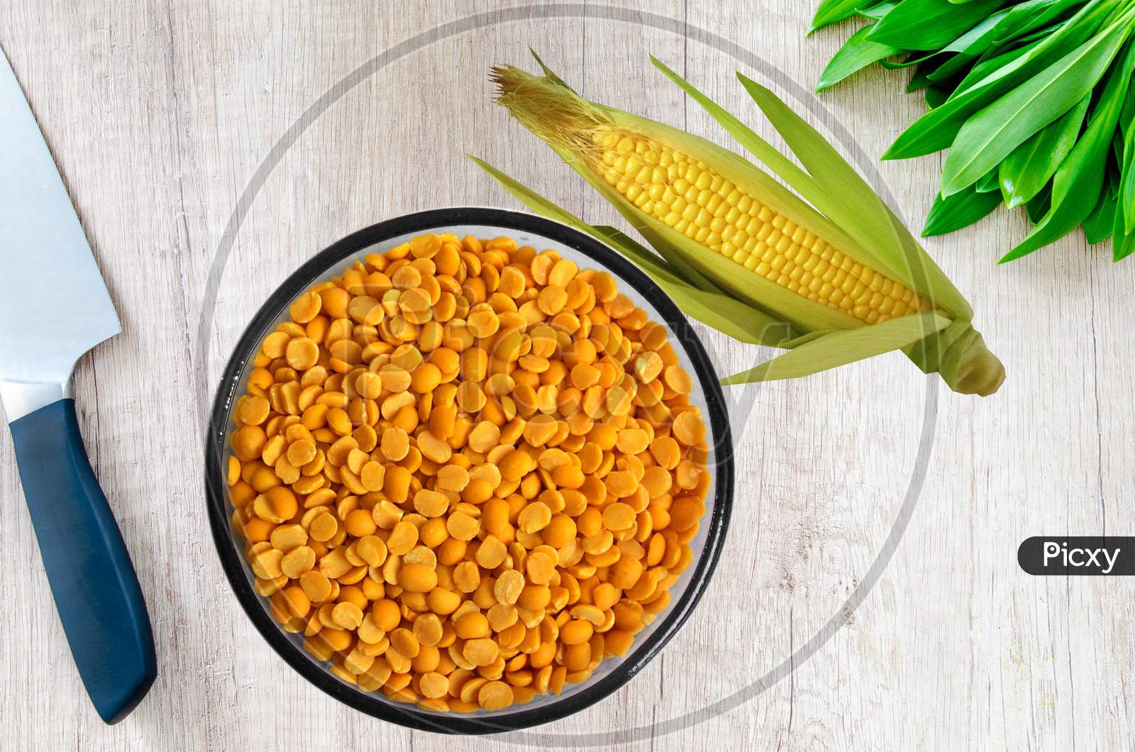 Yellow chopped peas in a bowl and corn on wooden background.Yellow split chickpea peas boot chana dal lentil pulse bean on wooden background,top view.healthy food.