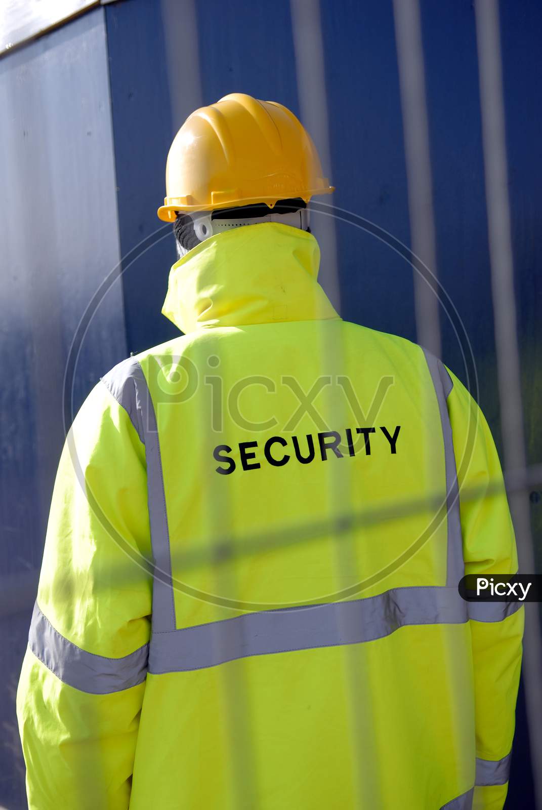Security Worker Behind Metal Fencing Protecting Property.