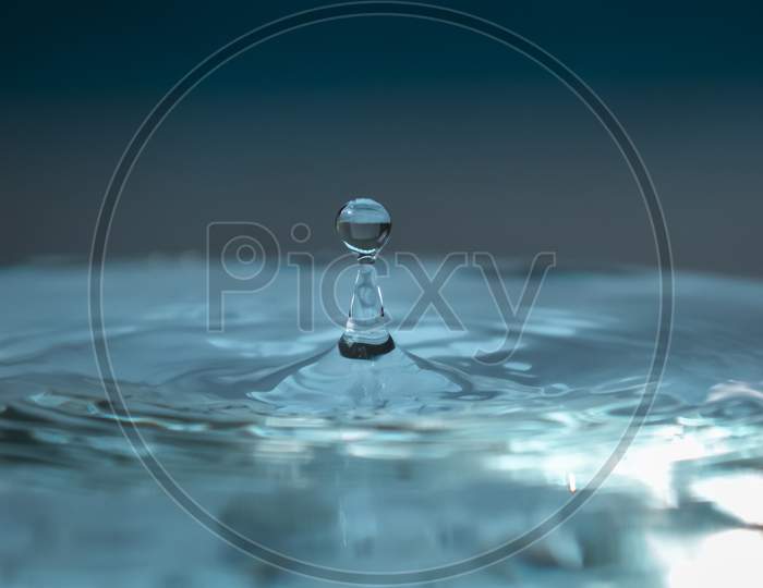 Water Droplet Rises After Falling On Blue Surface