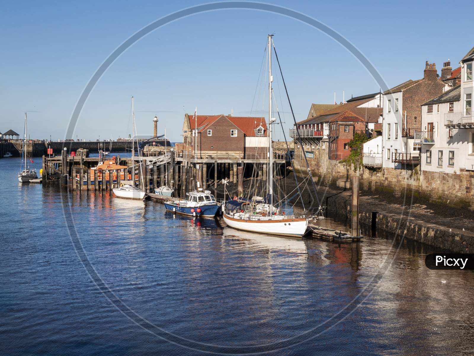 The harbour at Whitby with the buildings by the quayside and boats moored up.