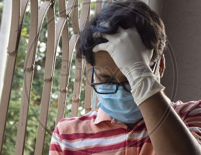 An Indian Or Asian Person Wearing Nose Mask And Hand Gloves Feeling Depression After Staying At Home During Lockdown Due To Covid-19 Or Corona Virus Outbreak