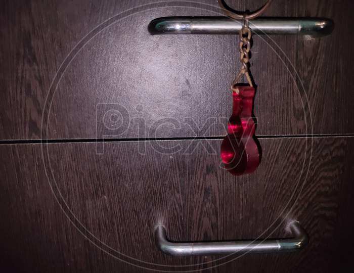 A Hanging Red Guitar Key-Chain In Low Light Condition