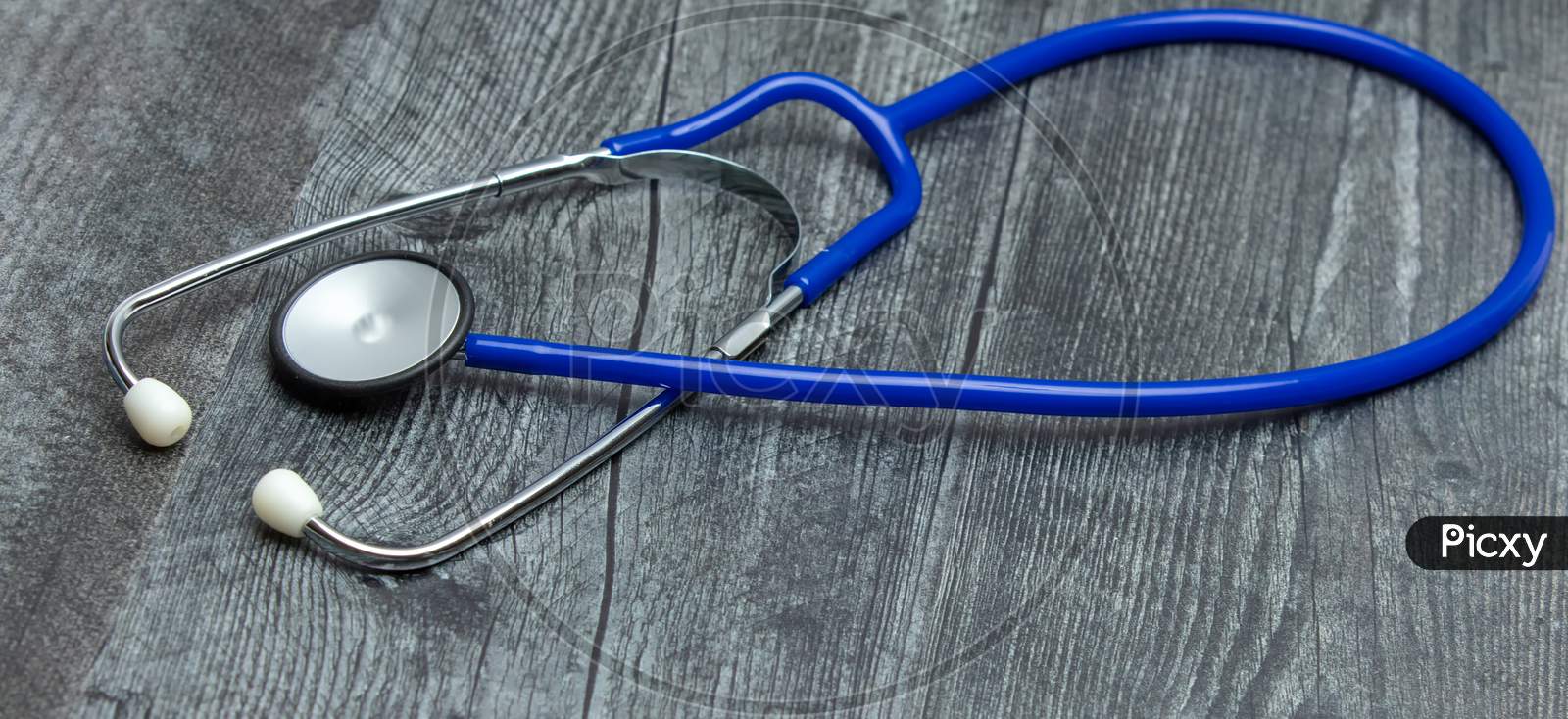 A Blue Medical Stethoscope Isolated On A Wooden Table.