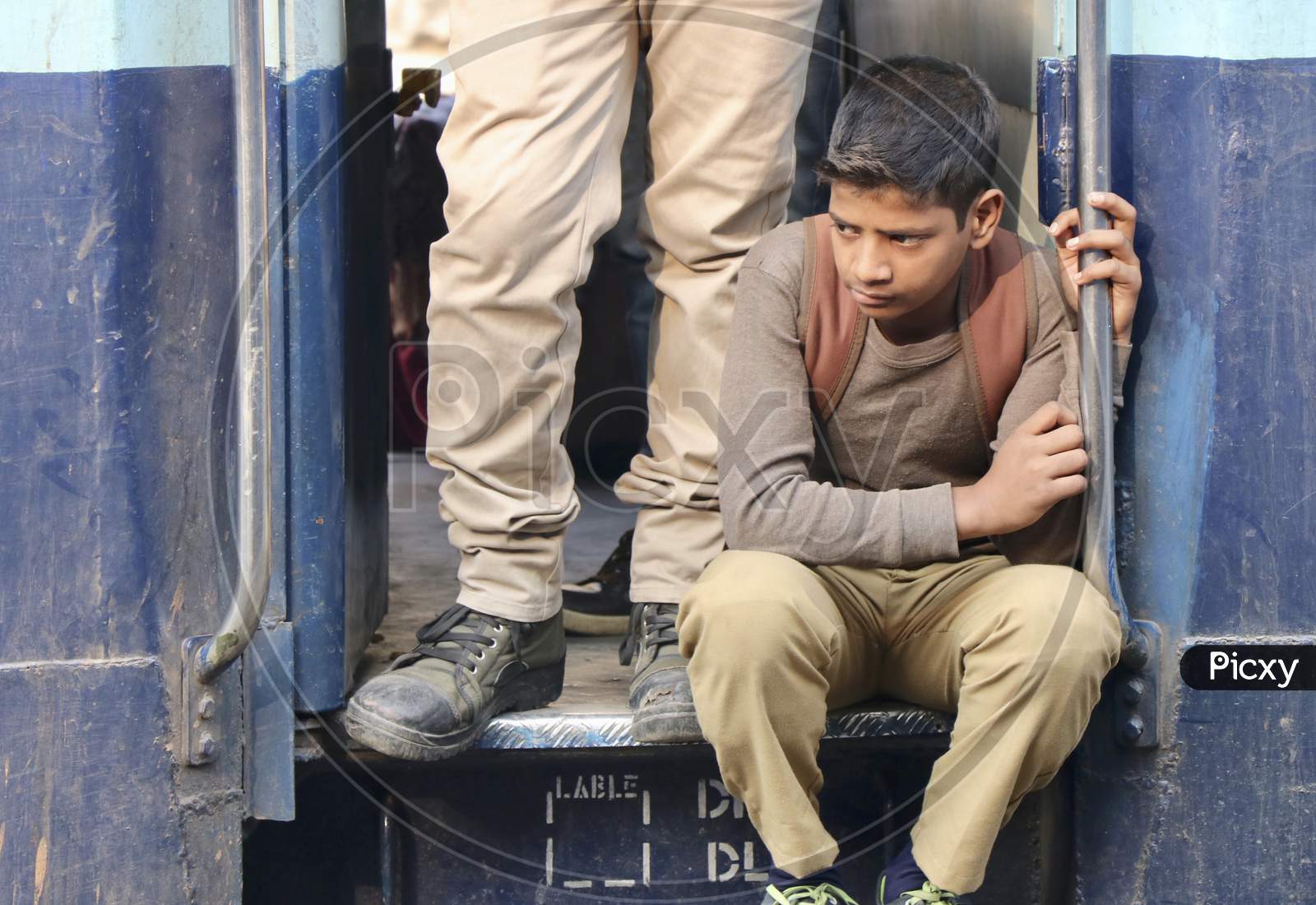 Boy sitting on the gate of the train waiting for it to start
