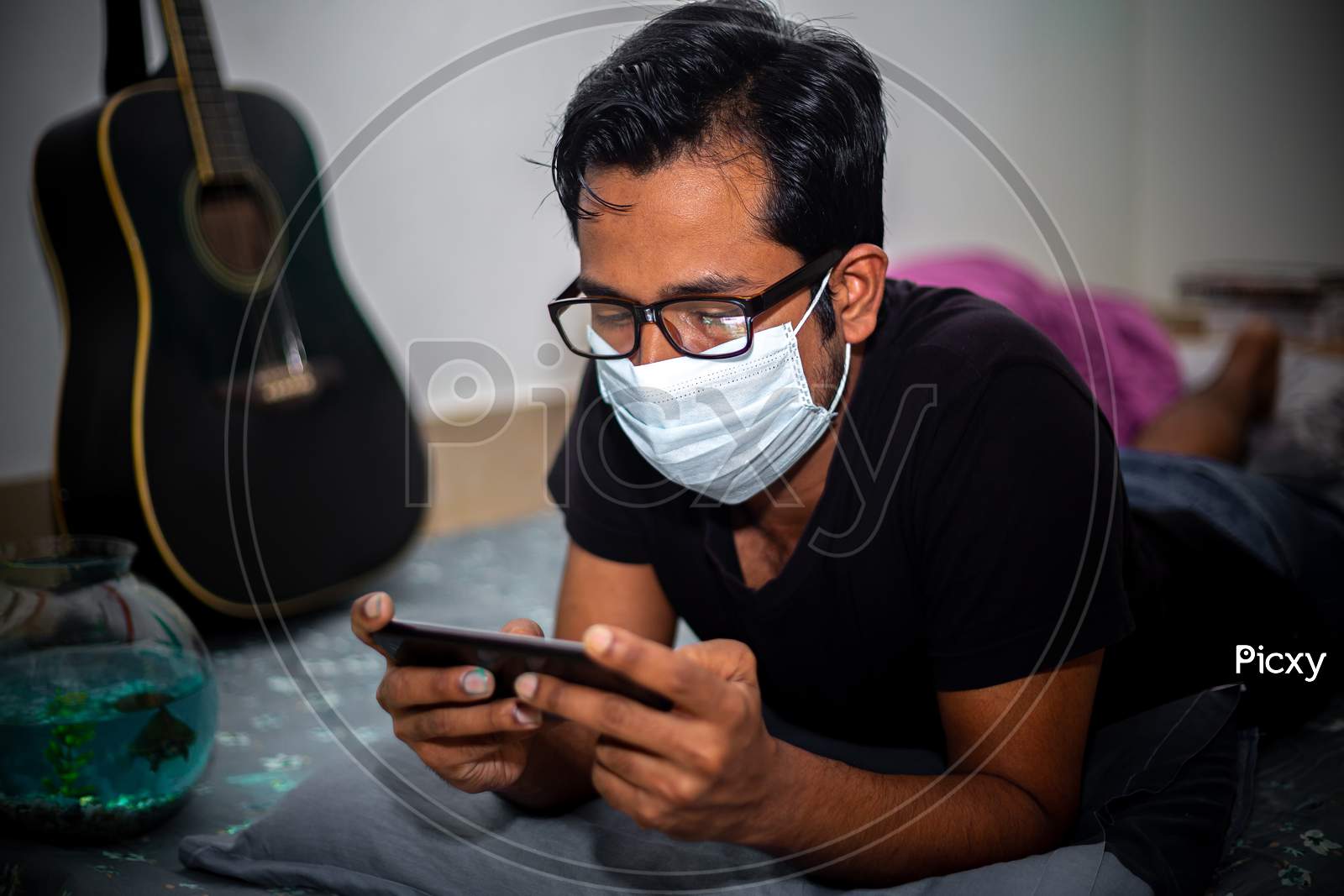 Bangladesh – April 14, 2020: A Surgical Mask-Wearing Young Man Was Playing Mobile Games On His Own Home Due To Coronavirus Home-Quarantine At Dhaka.