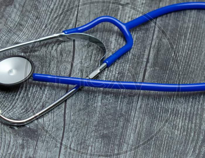 A Blue Medical Stethoscope Isolated On A Wooden Table.