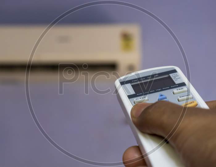 Operating An Air Conditioner With A Remote Held In Hand In Summer During Corona Virus Outbreak