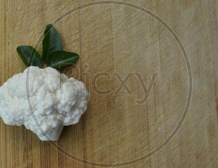 Pieces Of Cauliflower And Curry Leaf On Wooden Background.
