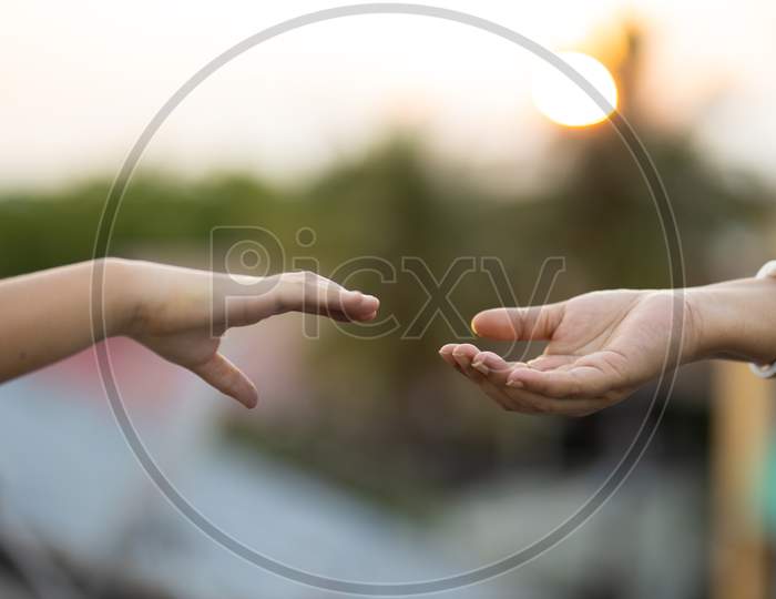 Woman And Child Holding Hands Outdoors At Sunset