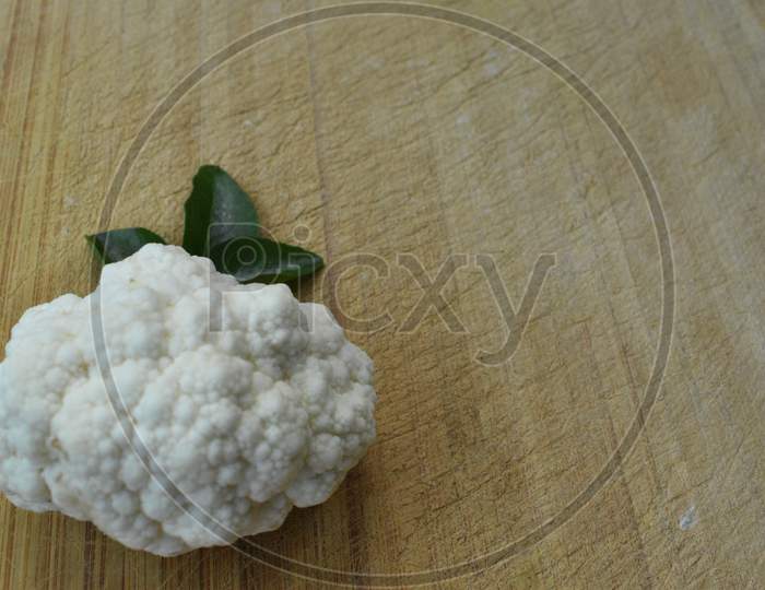 Pieces Of Cauliflower And Curry Leaf On Wooden Background.