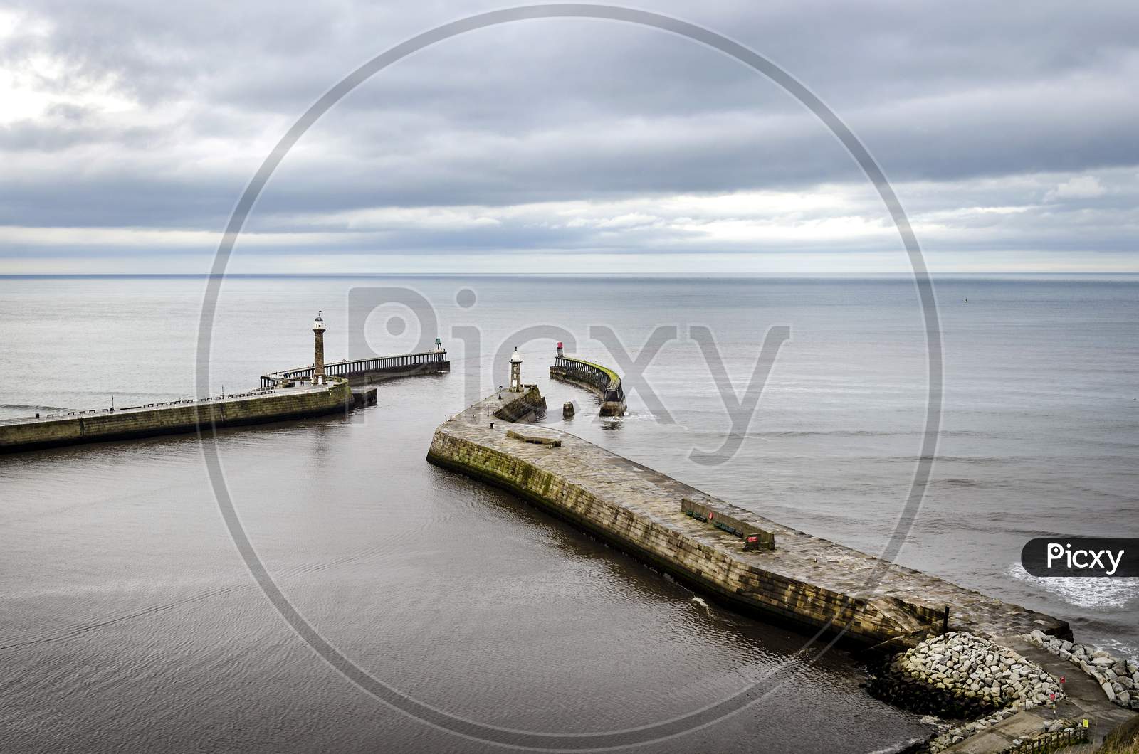 A view of Whitby harbour showing the entrance and lighthouse as seen from above.