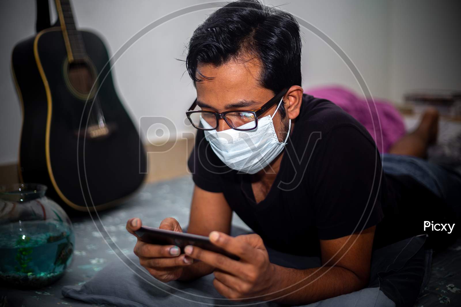 A Surgical Mask-Wearing Young Man Was Playing Mobile Games On His Own Home Due To Coronavirus Home-Quarantine At Dhaka.
