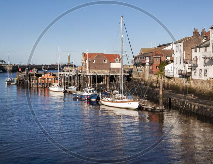 The harbour at Whitby with the buildings by the quayside and boats moored up.