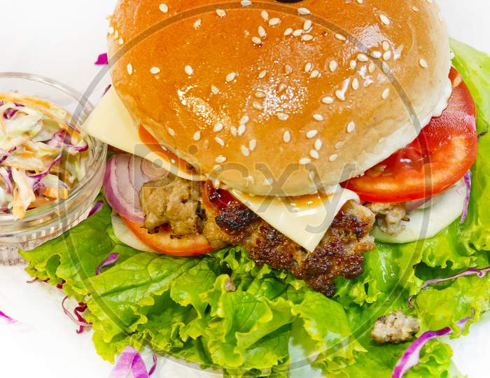 A Big Size Burger Patties From Ground Beef With Lettuce Leaf And Coleslaw Salad.