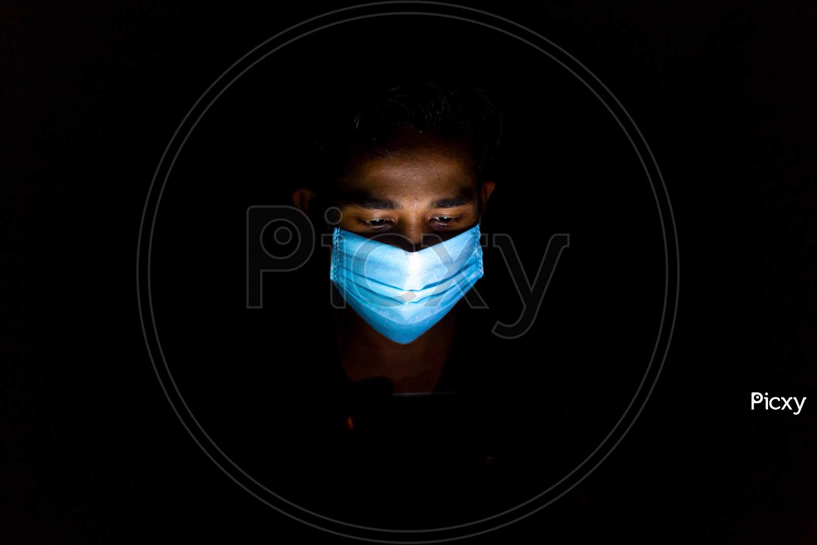 Bangladesh – April 14, 2020: A Blue Surgical Mask-Wearing Young Man Was Playing Mobile Games At Dhaka.